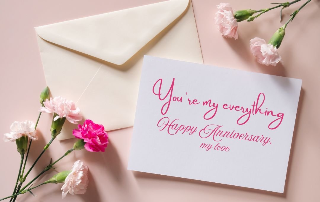 "Anniversary card with the message 'You're my everything. Happy Anniversary, my love,' surrounded by pink and white carnations and an envelope